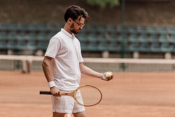 bel giocatore di tennis in stile retrò in piedi con palla da tennis e racchetta in campo
 - Foto, immagini