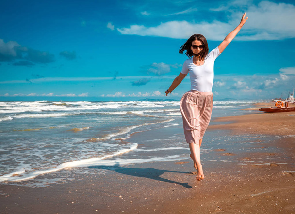 Mädchen läuft am Meer entlang. Urlaubskonzept mit Kopierraum auf Meeresgrund. Sommerstimmung. - Foto, Bild