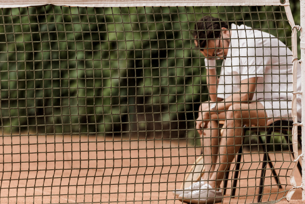 jugador de tenis sentado en la silla encima de la red en la cancha de tenis
 - Foto, Imagen
