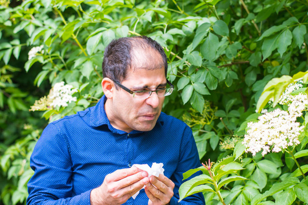 un uomo di mezza età vicino a un albero con fiori, è allergico al polline
 - Foto, immagini