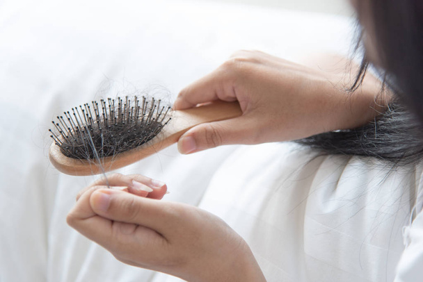 женщина показать свою щетку для предсетационной проблемы выпадения волос и глядя на ее волосы
 - Фото, изображение