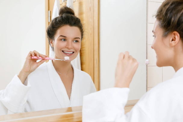 Woman cleaning her teeth in the bathroom - Φωτογραφία, εικόνα