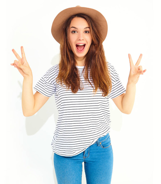 Portrait of young stylish laughing girl model in casual summer clothes in brown hat with natural makeup isolated on white background. Showing peace sign - Valokuva, kuva