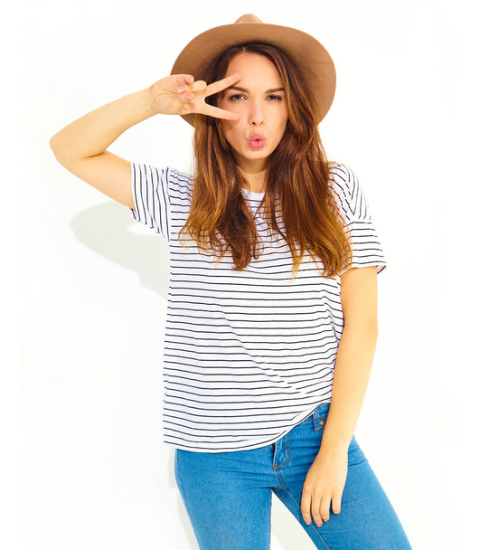 Portrait of young stylish laughing girl model in casual summer clothes in brown hat with natural makeup isolated on white background. Showing peace sign - Fotó, kép
