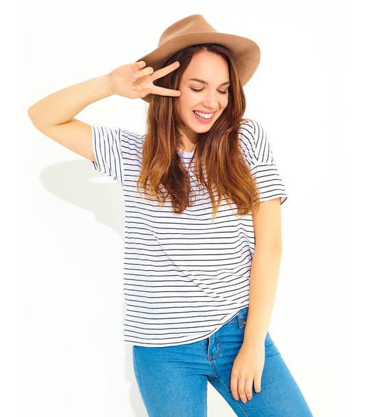 Portrait of young stylish laughing girl model in casual summer clothes in brown hat with natural makeup isolated on white background. Showing peace sign - Foto, Imagem