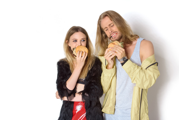 hungry stylish young couple eating tasty burgers on white - Fotoğraf, Görsel