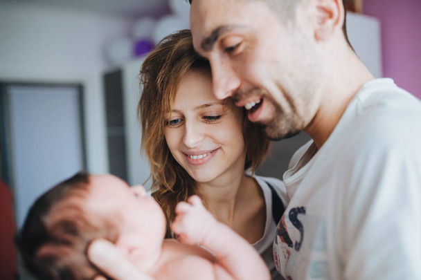 Happy mother and father talking to their newborn baby and playing with her - Foto, Imagen