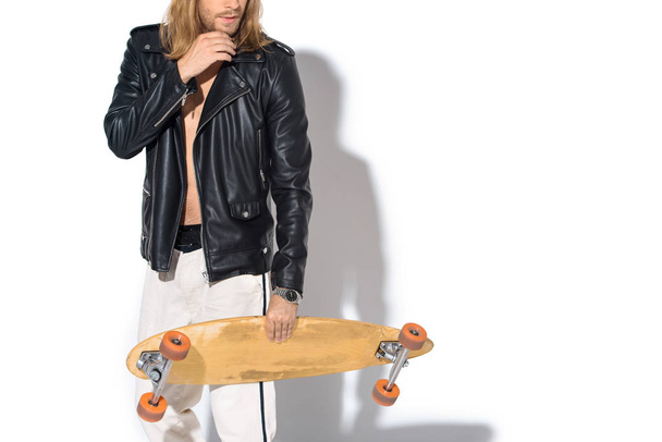 handsome young man in leather jacket with longboard on white - Fotó, kép