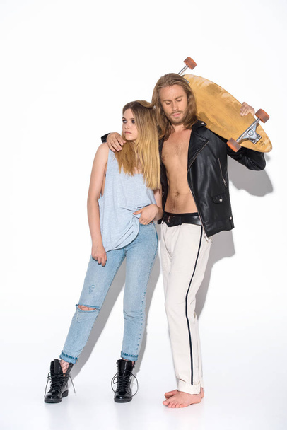 pareja joven de moda con monopatín abrazando en blanco
 - Foto, imagen