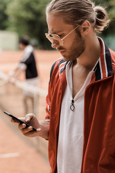 retro styled tennis player looking at smartphone at court - Photo, Image
