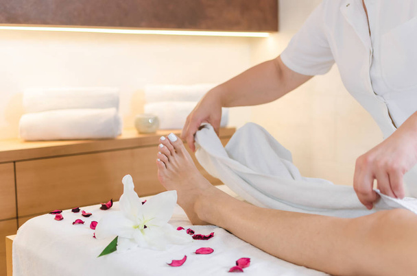 Masseur op imposante spa salon klaarmaken jonge vrouwen voor been en voet massagebehandeling en pedicure. - Foto, afbeelding