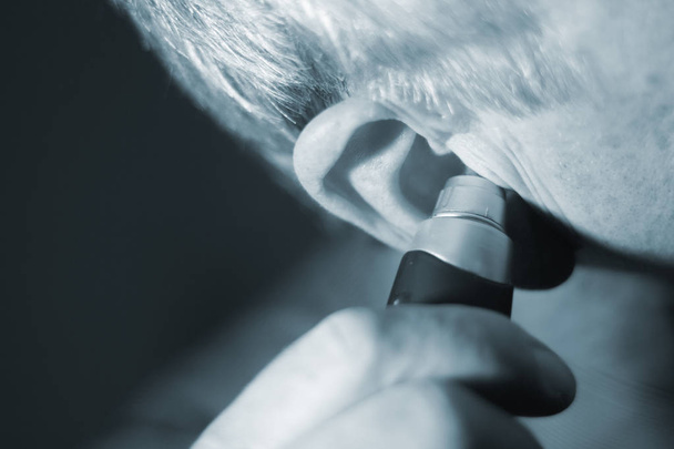 Senior citizen man cutting inner ear hair with electric cutter. - Photo, Image