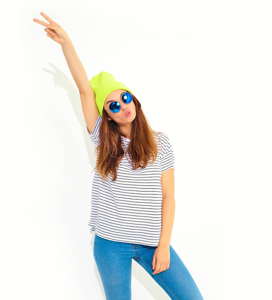 Portrait of young stylish girl model in casual summer clothes in yellow beanie hat isolated on white. Hands in air - 写真・画像