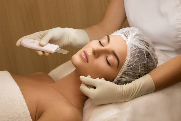 Beautiful woman in professional beauty spa salon during ultrasonic facial cleansing procedure - Foto, Imagen