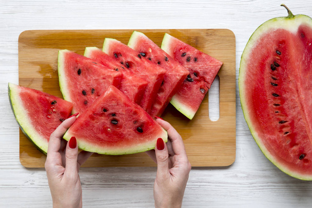 Women's hands hold a piece of watermelon, view from above.  - Photo, Image