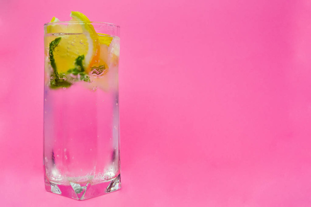 Vaso de agua, limón y menta sobre fondo rosa
. - Foto, Imagen