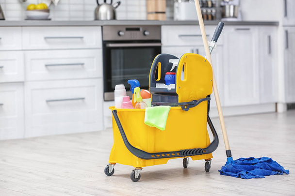 Mop bucket with cleaning supplies in kitchen - Фото, зображення