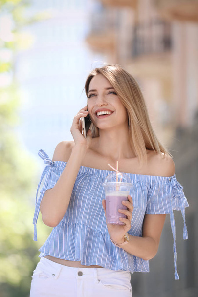 Young woman with plastic cup of healthy smoothie outdoors - Zdjęcie, obraz