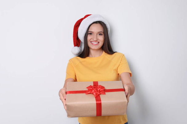 Young woman with Christmas gift on white background - Foto, afbeelding