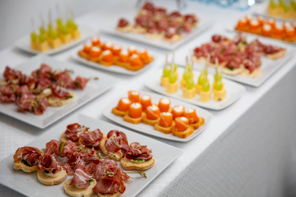 Disporre una varietà di tartine e snack su un tavolo del ristorante per celebrare il matrimonio o altro evento solenne
. - Foto, immagini
