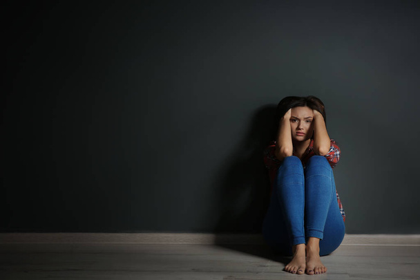 Jeune femme déprimée assise sur le sol dans l'obscurité
 - Photo, image