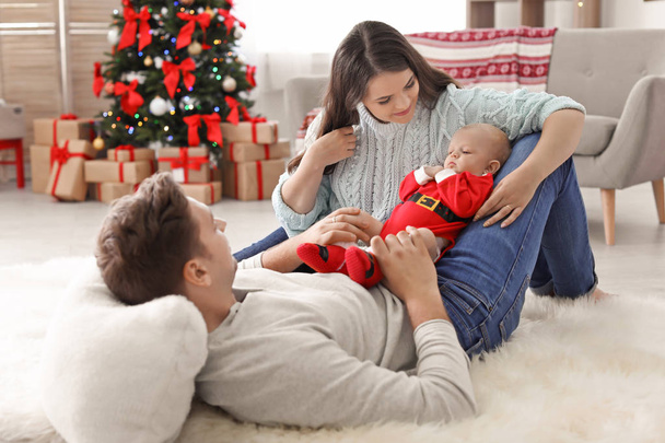 Onnellinen pari vauvan kanssa juhlii joulua yhdessä kotona
 - Valokuva, kuva