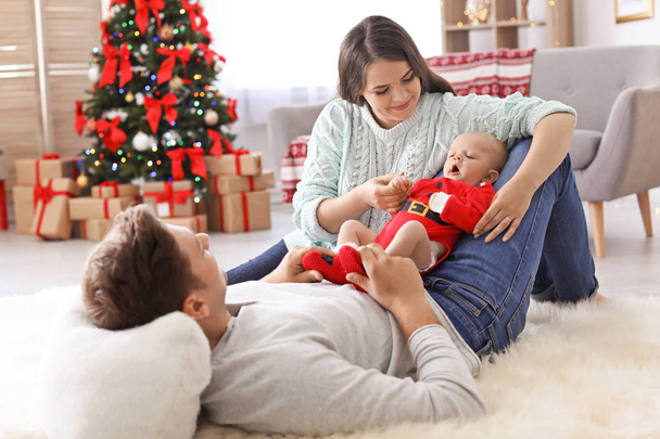Happy couple with baby celebrating Christmas together at home - Фото, изображение