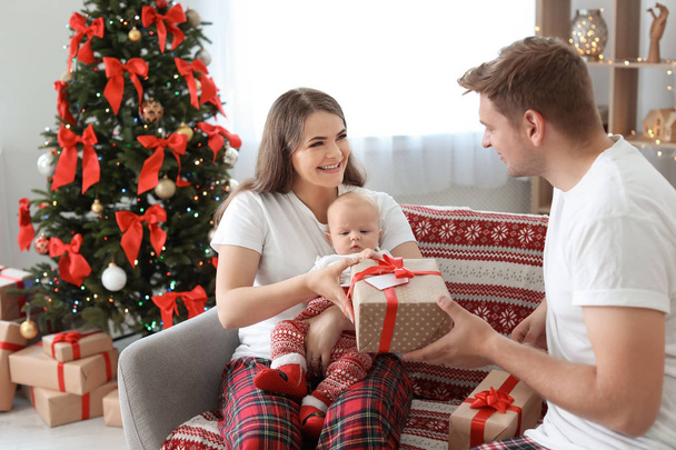 Joyeux couple avec bébé célébrant Noël ensemble à la maison
 - Photo, image