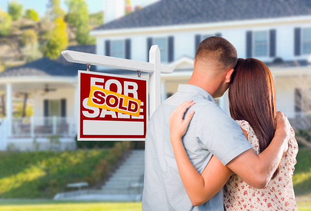 Military Couple Looking At House with Sold For Sale Real Estate Sign In Front. - Photo, Image