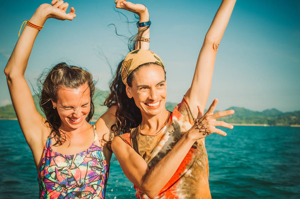 Two happy young woman jumping and laughing on the beach. Best friends having fun - Фото, зображення