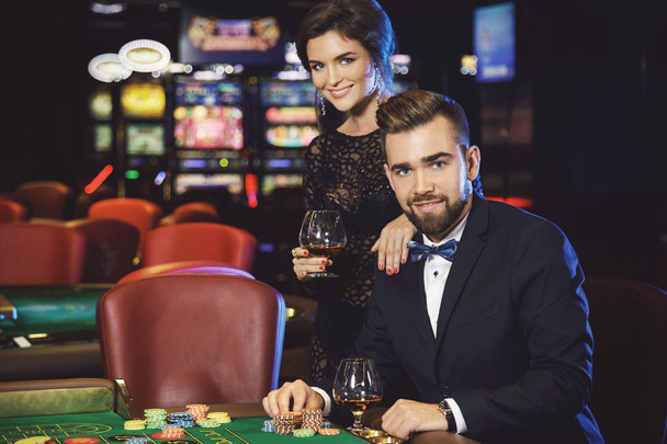 Beautiful well dressed couple playing roulette in the casino - Foto, imagen
