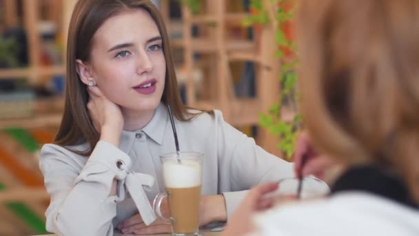 Duas jovens mulheres conversando e bebendo café sentado no café. - Filmagem, Vídeo