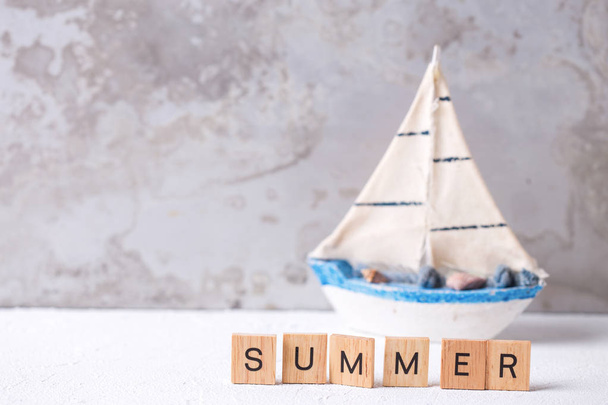 Word summer from wooden blocks and boat toy against grey wall - Foto, Imagem