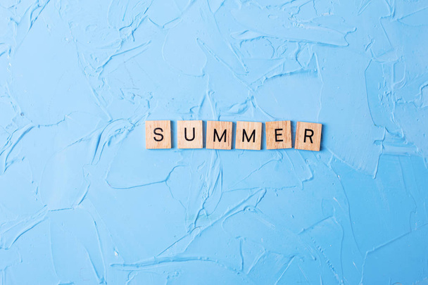 Word summer from wooden blocks on blue textured background - Foto, afbeelding