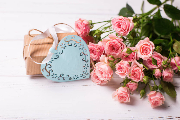 Pink roses flowers, decorative heart and box with present on white wooden background - Фото, зображення