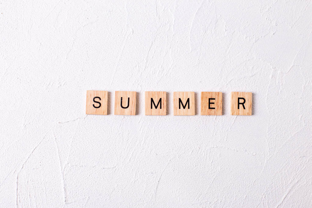 Word summer from wooden blocks on white textured background - Foto, imagen