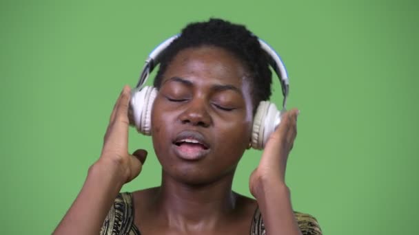 Young beautiful African woman listening to music - Filmati, video