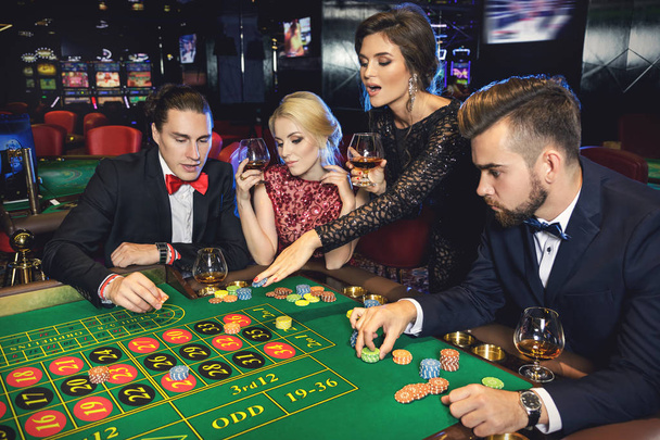 Young rich people playing roulette in casino - Foto, imagen