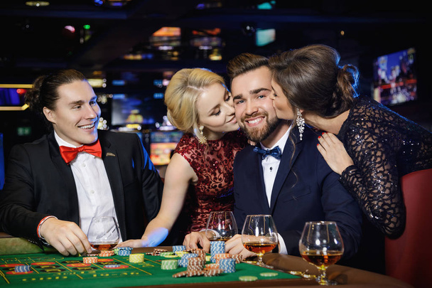 Happy guy was kissed by two beautiful girls after win in roulette - Фото, зображення