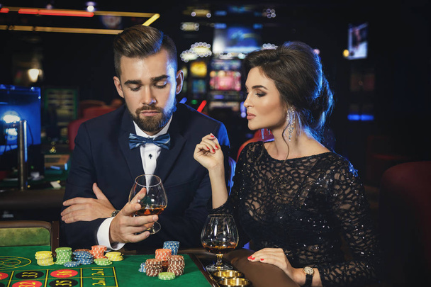 Beautiful well dressed couple playing roulette in the casino - Φωτογραφία, εικόνα