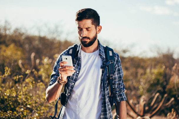 Hiker using mobile phone during trekking in the desert. - Fotoğraf, Görsel