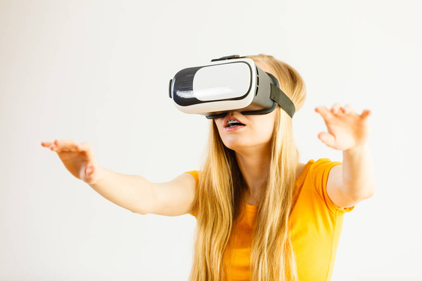 Young woman wearing virtual reality goggles headset, vr box, stretching arms. Connection, technology, new generation and progress concept. Studio shot on gray - Photo, Image