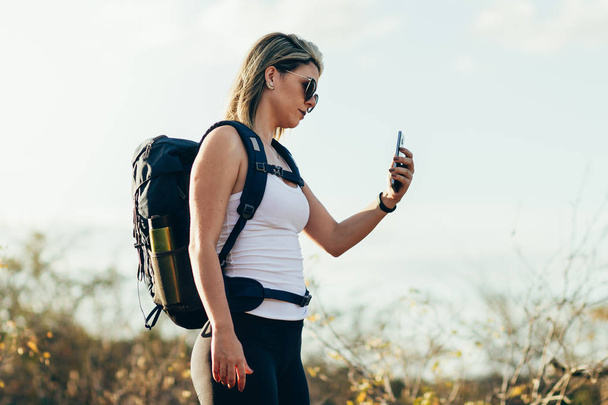 Hiker using mobile phone during trekking in the desert. - Zdjęcie, obraz