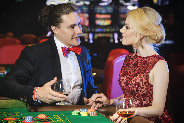 Beautiful well dressed couple playing roulette in the casino - Photo, image