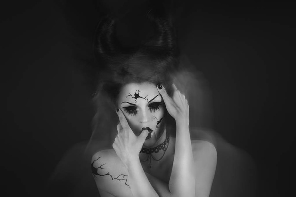 Model in creative image for Halloween. Spooky porcelain doll with horns on her head. - Foto, imagen