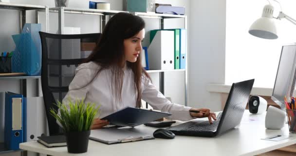 zakenvrouw die op laptop werkt en schrijven op papier in moderne kantoren - Video