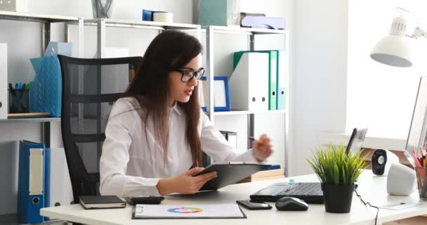 zakenvrouw in zwarte glazen vullen documenten en werken op de laptop in moderne kantoren - Video