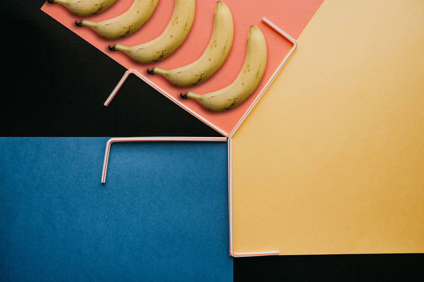 Una fotografía creativa con bananas y pequeños tubos sobre un fondo brillante
 - Foto, imagen