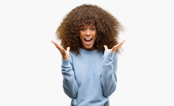 Έθεσε αφρικανική αμερικανική γυναίκα, φορώντας ένα πουλόβερ γιορτάζει τρελό και κατάπληκτος για την επιτυχία με τα χέρια και τα μάτια ανοιχτά, κραυγάζοντας ενθουσιασμένος. Νικητής έννοια - Φωτογραφία, εικόνα