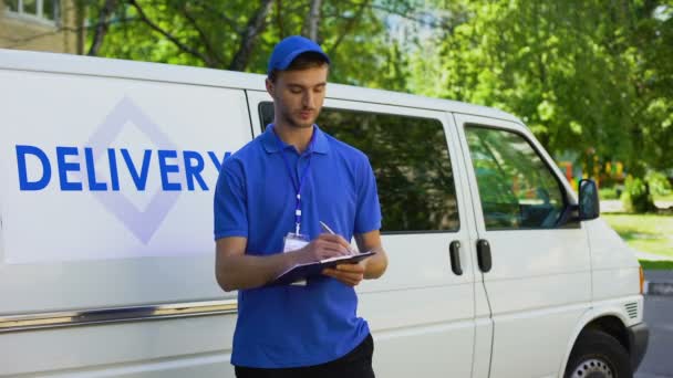 Parcel delivery worker filling report and smiling, part-time job, occupation - Felvétel, videó